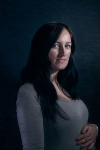 Portrait of woman against black background