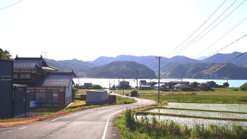 Road by buildings against sky