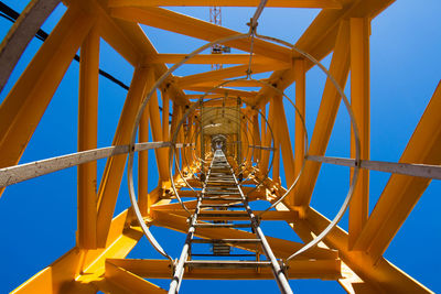 Low angle view of a crane ladder against blue sky