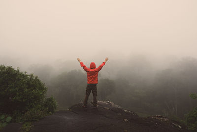 Rear view of man standing on mountain during foggy weather