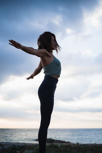 A woman with arms backwards performing yoga exercises in a natural setting.