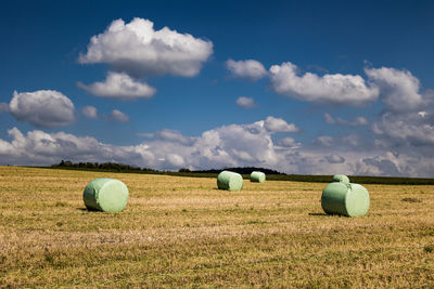 Hay bales on field against sky