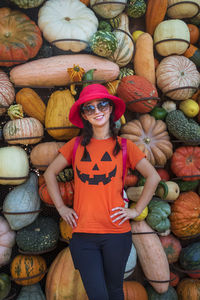 Portrait of smiling woman standing by pumpkins