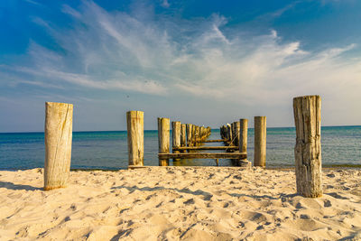 Wooden posts on beach against sky