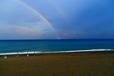 Scenic view of beach against rainbow in sky