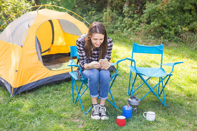 Full length of young woman sitting on tent