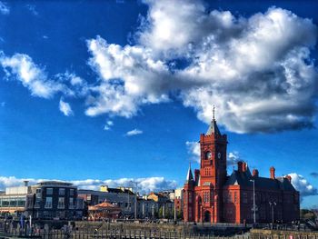 Buildings in city against cloudy sky