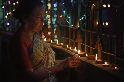 A hindu woman decorating her home with diyas on the evening of diwali and kali puja.