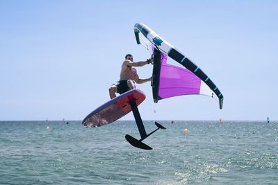 Young man enjoying hydrofoil in sea on sunny day