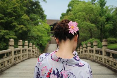 Rear view of woman with pink flowers against trees