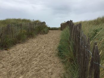 Footpath leading towards field against sky