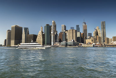 Sea by modern buildings against clear sky