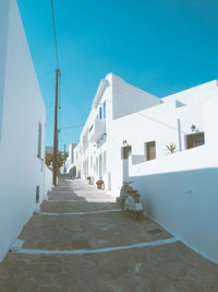 Empty road amidst buildings against clear blue sky