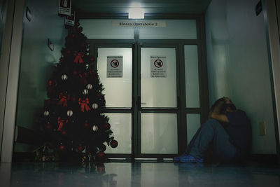 Man with head in hands sitting at hospital during christmas