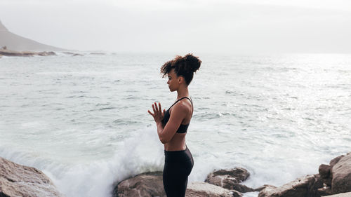 Side view of young woman sitting at beach