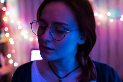 Close-up of young woman against illuminated lights at home