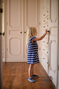 Full length of girl standing against door at home