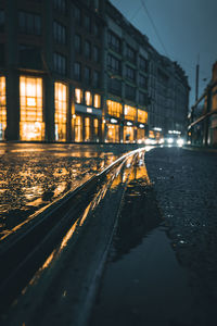 Illuminated railroad tracks by buildings in city at night