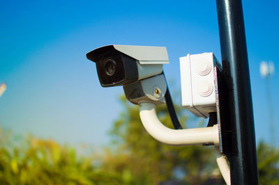 Low angle view of surveillance camera against blue sky