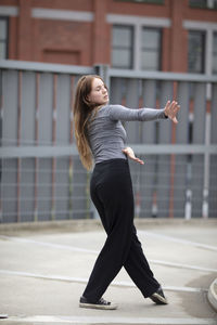 Full length of woman with arms raised in city