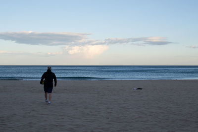 Rear view of man on beach against sky