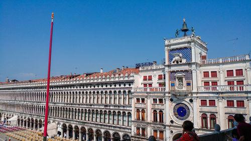 Group of people in front of building against clear blue sky