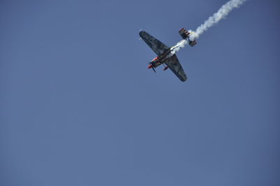 Low angle view of airplane flying against clear blue sky