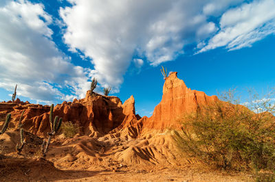 Low angle view of rock formations at desert against cloudy sky