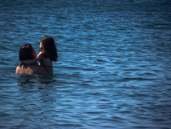 Rear view of mother and daughter in sea