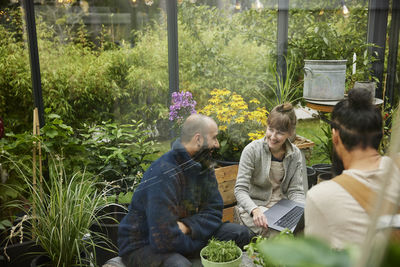 Smiling friends sitting in greenhouse