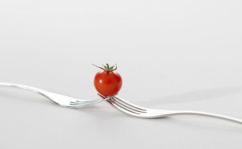 Close-up of red berries on table against white background