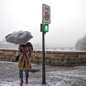 Rear view of man with umbrella standing on snow covered landscape