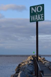 Information sign on rock by sea against sky