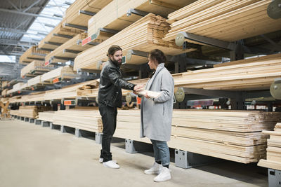 Couple examining wooden plank while standing by shelves at hardware store