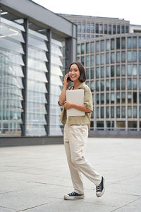 Portrait of young woman standing in city