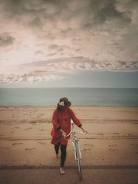 Woman with bicycle walking on beach