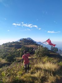 People on field by mountain against sky