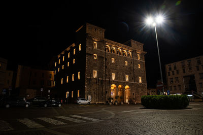 Low angle view of illuminated street amidst buildings in city at night