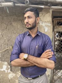 Portrait of young man standing against wall