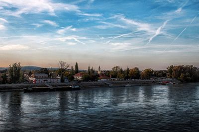 Scenic view of river by buildings against sky