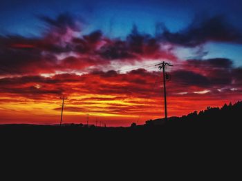 Low angle view of silhouette electricity pylon against sky during sunset