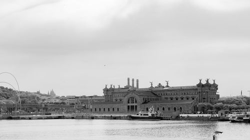 Buildings by river against sky