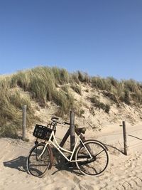 Bicycle parked on land against clear blue sky