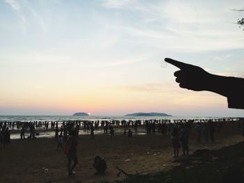 Silhouette people on beach against sky during sunset