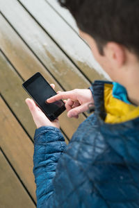 High angle view of man using smart phone while standing outdoors