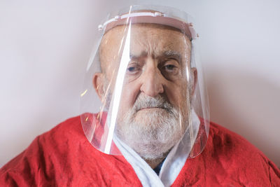 Senior man wearing a protective visor and santa claus suit