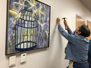 Woman hammering nail into wall by painting