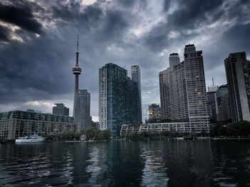 Modern buildings by river against sky in city