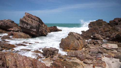 Rocks on shore by sea against sky