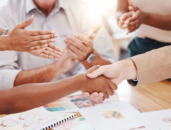 Midsection of business people stacking hands